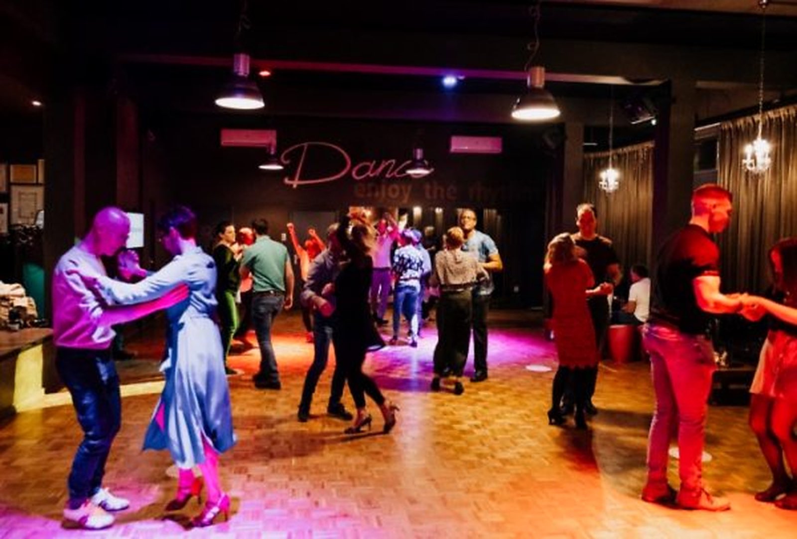 Een volle dansvloer bij Swing Inn: paren dansen onder gekleurd licht